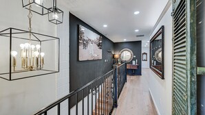 A modern interior with a staircase, a chandelier, and a framed photograph on the wall. - Stellar Craig Apartment - Walk to Restaurants! (Craig)