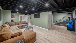 Een ruime woonkamer met een hoekbank, een glazen salontafel en een trampoline op de achtergrond.