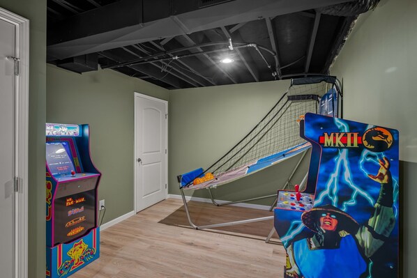 Ein Zimmer mit einem Pac-Man-Spielautomaten, einer Hängematte und einem Charakterposter.