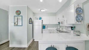 A modern kitchen with white cabinetry, a central island with bar stools, and decorative wall art.
