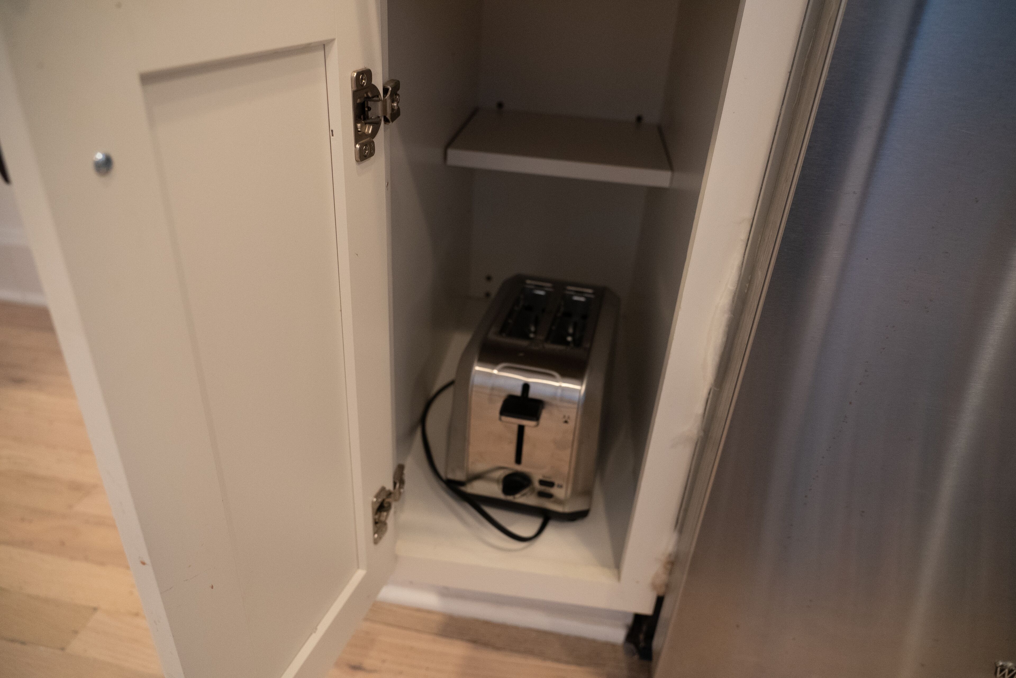 A small kitchen area with a toaster on a shelf.