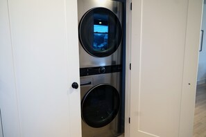 A compact, modern laundry room with two stacked washing machines and a dryer, enclosed in a white door.