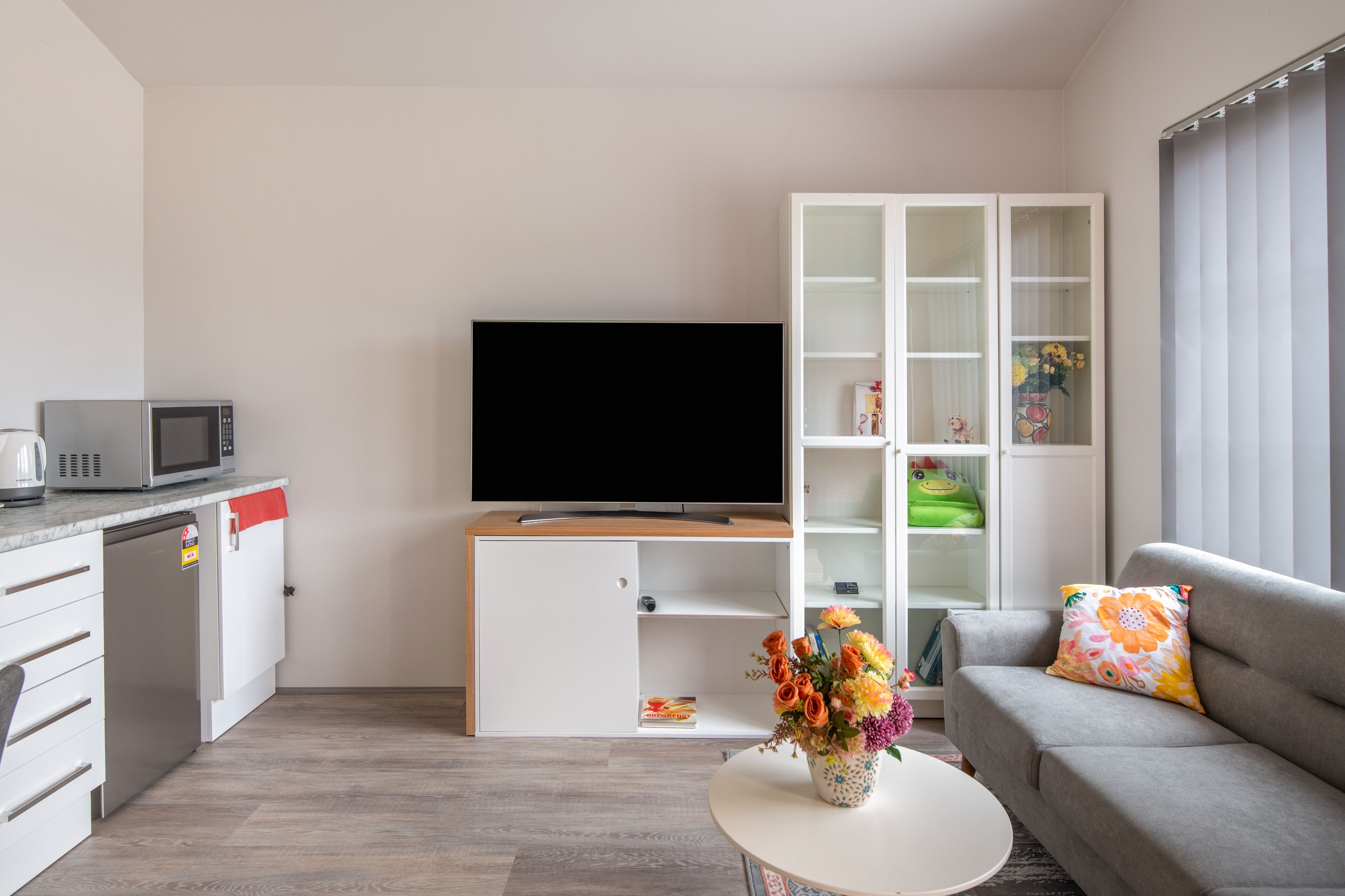 A modern living room with a flat-screen TV, a sofa, a coffee table, and a cabinet with glass doors.