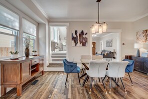 Un comedor moderno con suelo de madera, una mesa de vidrio y sillas azules y blancas.