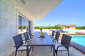 Eine Terrasse mit Tisch und Stühlen, einer Obstschale und einem Schwimmbecken.