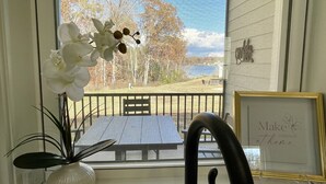 Vista a través de una ventana con una orquídea blanca, una cita enmarcada y una barandilla metálica.