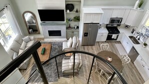 Una cocina moderna con armarios blancos, horno integrado y refrigerador de acero inoxidable.