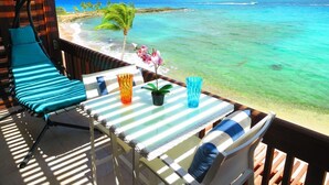A balcony with a view of the ocean, a table with chairs, and a hanging chair. - 🌴 2BR Sapphire Beachfront Newly Renovated Perfect for Family Washer/Dryer/WiFi (St Thomas)