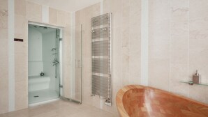 A modern bathroom with a glass shower enclosure, a wooden bathtub, and a chrome towel rack. - B&B in town center with private hammam (La Rochelle)