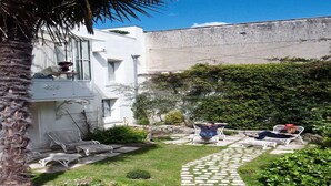 A courtyard with white walls, a palm tree, and outdoor seating. - B&B in town center with private hammam (La Rochelle)