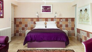 A bedroom with a checkered headboard, a bed with a purple bedspread, two bedside lamps, and a patterned rug. - Bed & Breakfast in the town center (La Rochelle)