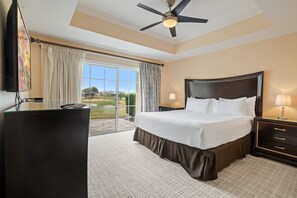 A hotel room with a large bed, a ceiling fan, a television, and a view of the outdoors.