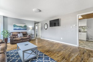 A living room with a brown leather sofa, a white coffee table, and a blue patterned rug. - Mid-Landing Inn (Colorado Springs)