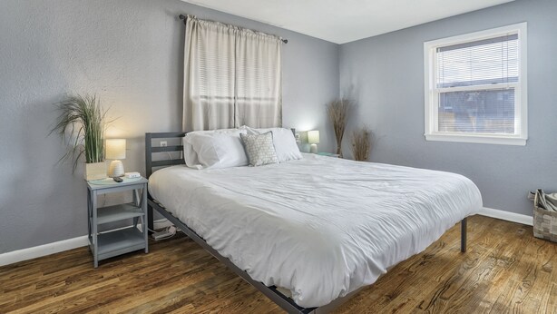 A bedroom with a bed, nightstand, lamp, and window. - Mid-Landing Inn (Colorado Springs)