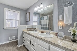 A bathroom with two sinks, a large mirror, and a towel rack. - Mid-Landing Inn (Colorado Springs)
