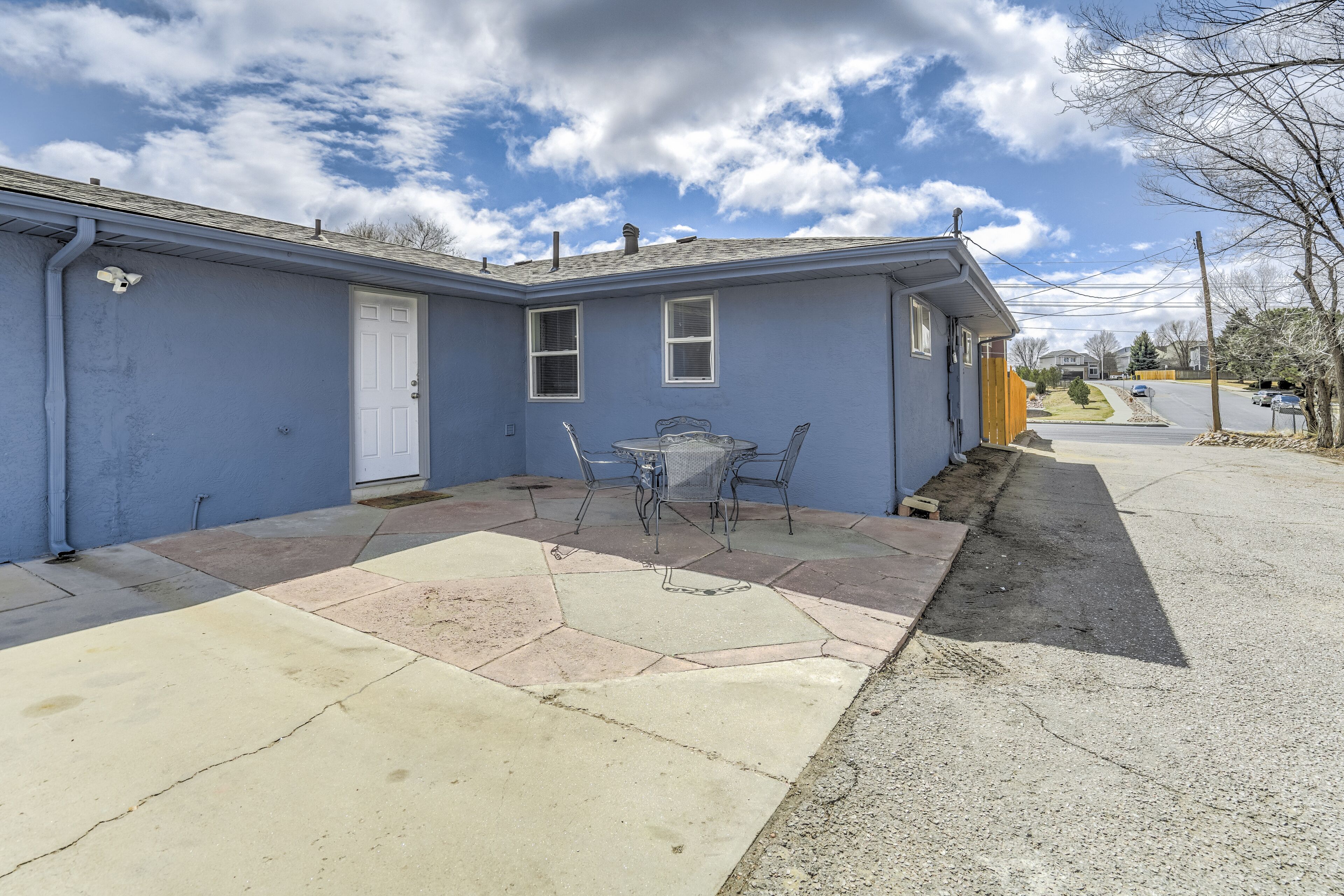 A residential house with a patio area featuring a table and chairs, a door, and a small window.