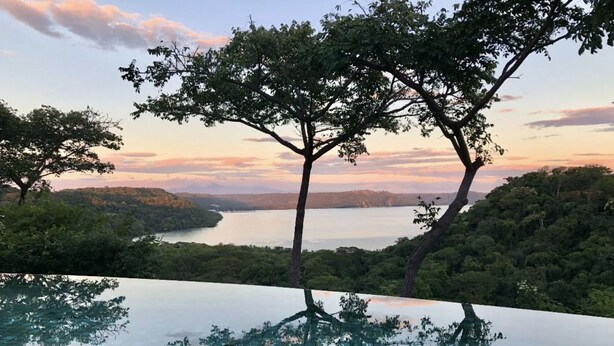 A infinity pool with a clear view of a lake and surrounding trees. - As Seen on CBS's Staycation•Resort & Beach Club Access•Concierge•Papagayo Luxury (Peninsula papagayo)