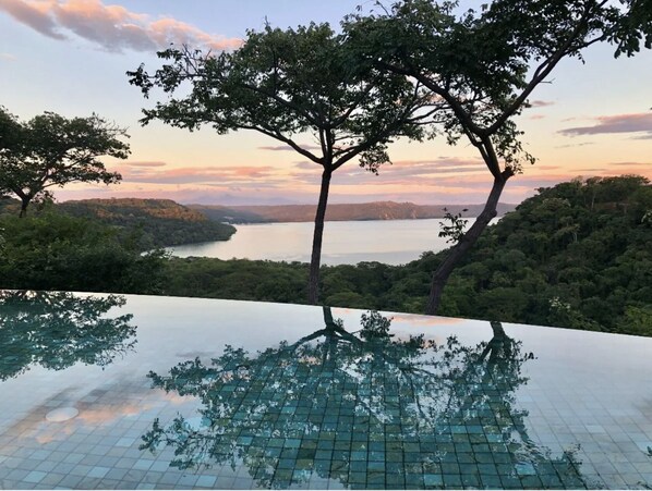 Ein Infinity-Pool mit freiem Blick auf einen See und die umliegenden Bäume.