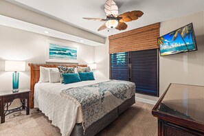 Ein Schlafzimmer mit Bett, Deckenventilator, Fernseher und einem Fenster mit Jalousien.