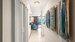 A hallway with a view to a balcony, a seating area, and artwork on the walls. - Luxury meets space in this Premium 1bd Oceanfront (Lahaina)