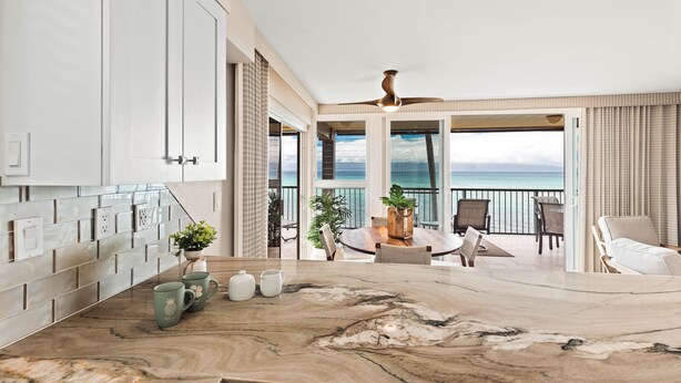 Eine moderne Küche mit Marmorarbeitsplatte, ein Essbereich mit Meerblick und ein Balkon mit Seeblick.