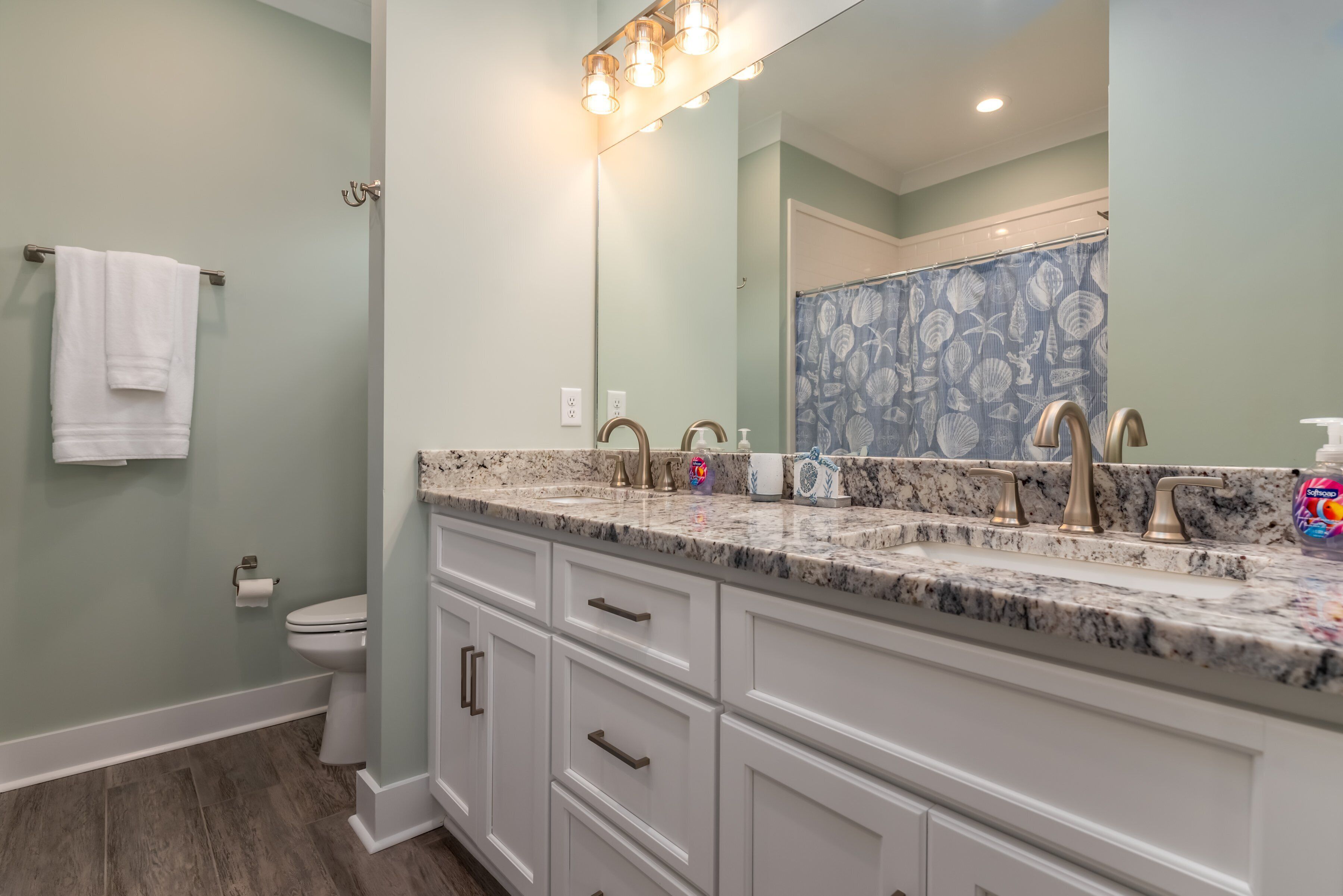 A bathroom with a marble countertop, a large mirror, and a toilet.