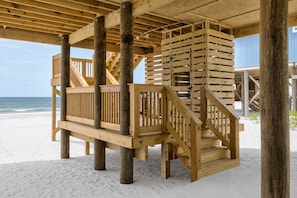 Een houten strandpaviljoen met een trap en leuningen.