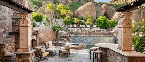 A patio area with stone flooring, outdoor seating, and a pool.
