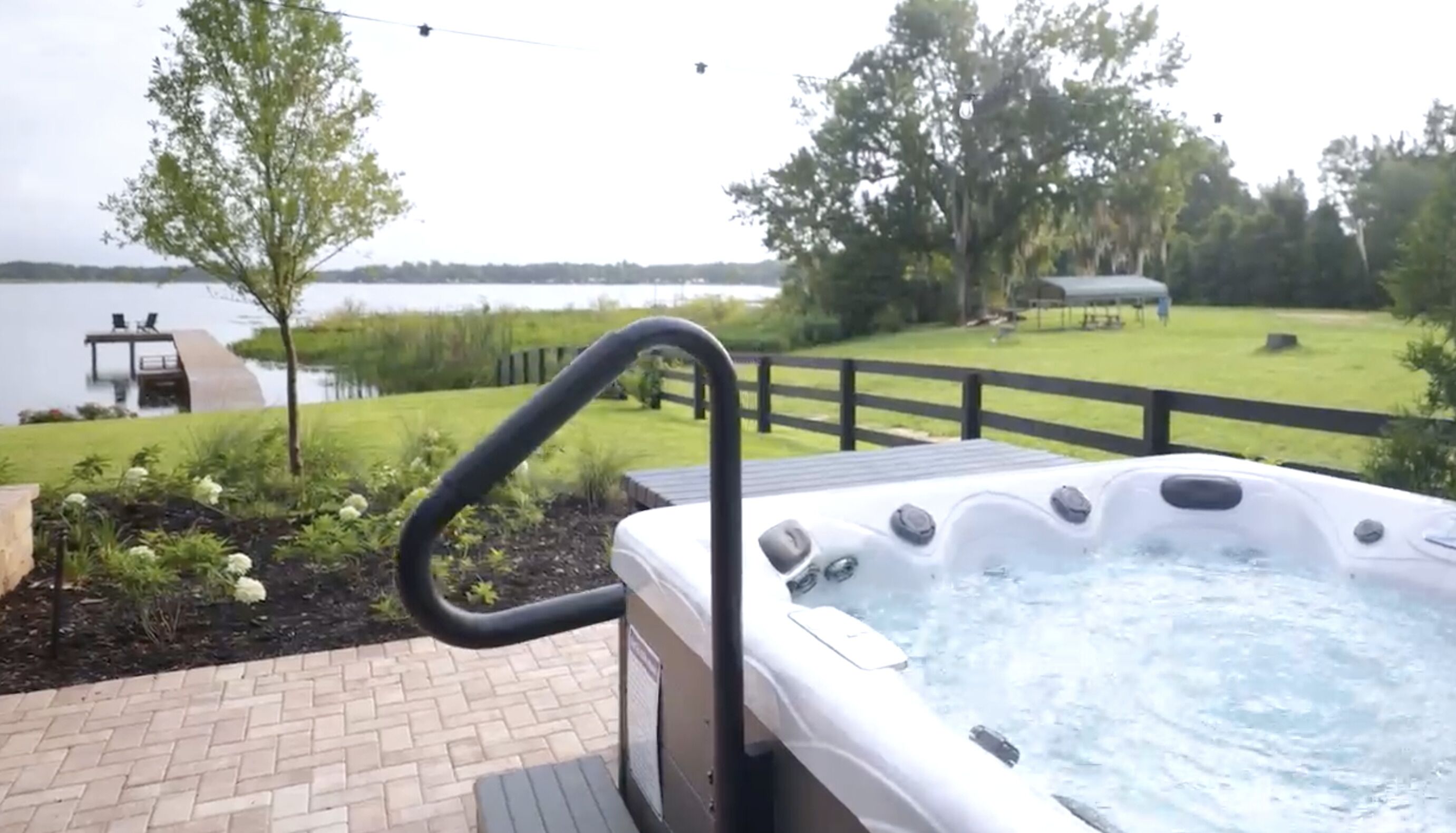 A hot tub with a wooden deck and a view of a lake.
