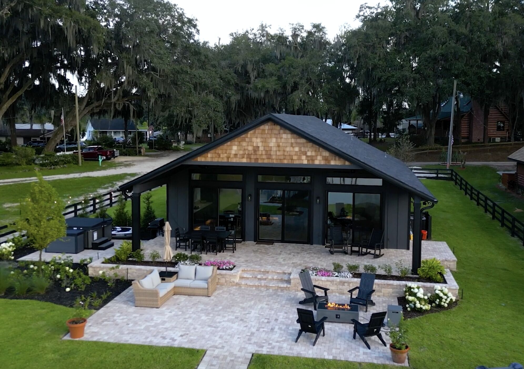 A modern outdoor patio area with a fireplace, seating, and a view of the surrounding landscape.