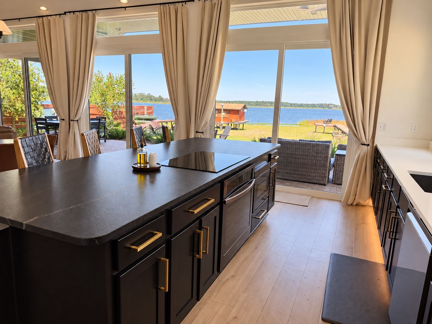 Una cocina moderna con una isla grande, vistas al exterior y un comedor con sillas y una mesa.