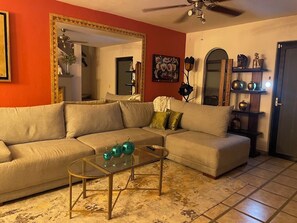 A living room with a beige sectional sofa, a glass coffee table, and a ceiling fan.