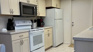 A kitchen with white cabinets, a microwave, a stove, and a refrigerator.