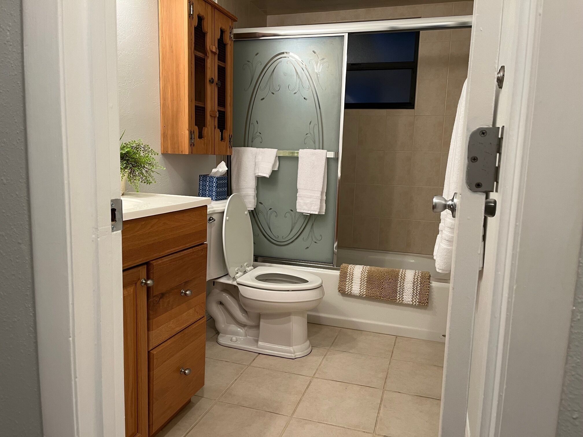 A bathroom with a toilet, a wooden cabinet, a towel rack, and a shower area.