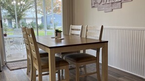A dining area with a wooden table and chairs, a chandelier, and a 'Family' sign on the wall.
