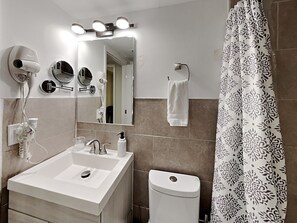Un baño con lavamanos, espejo, secador de pelo y barra para toallas.