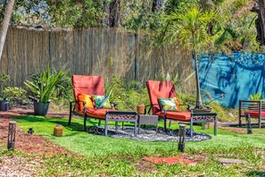 Un jardín con dos sillones rojos, una mesita y una planta decorativa.