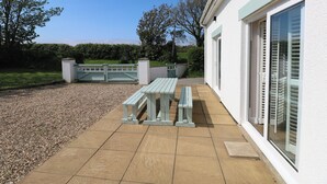 A patio with a table and benches, a gravel path, and a white building with a door and windows. - Yr Hen Ardd (Haverfordwest)