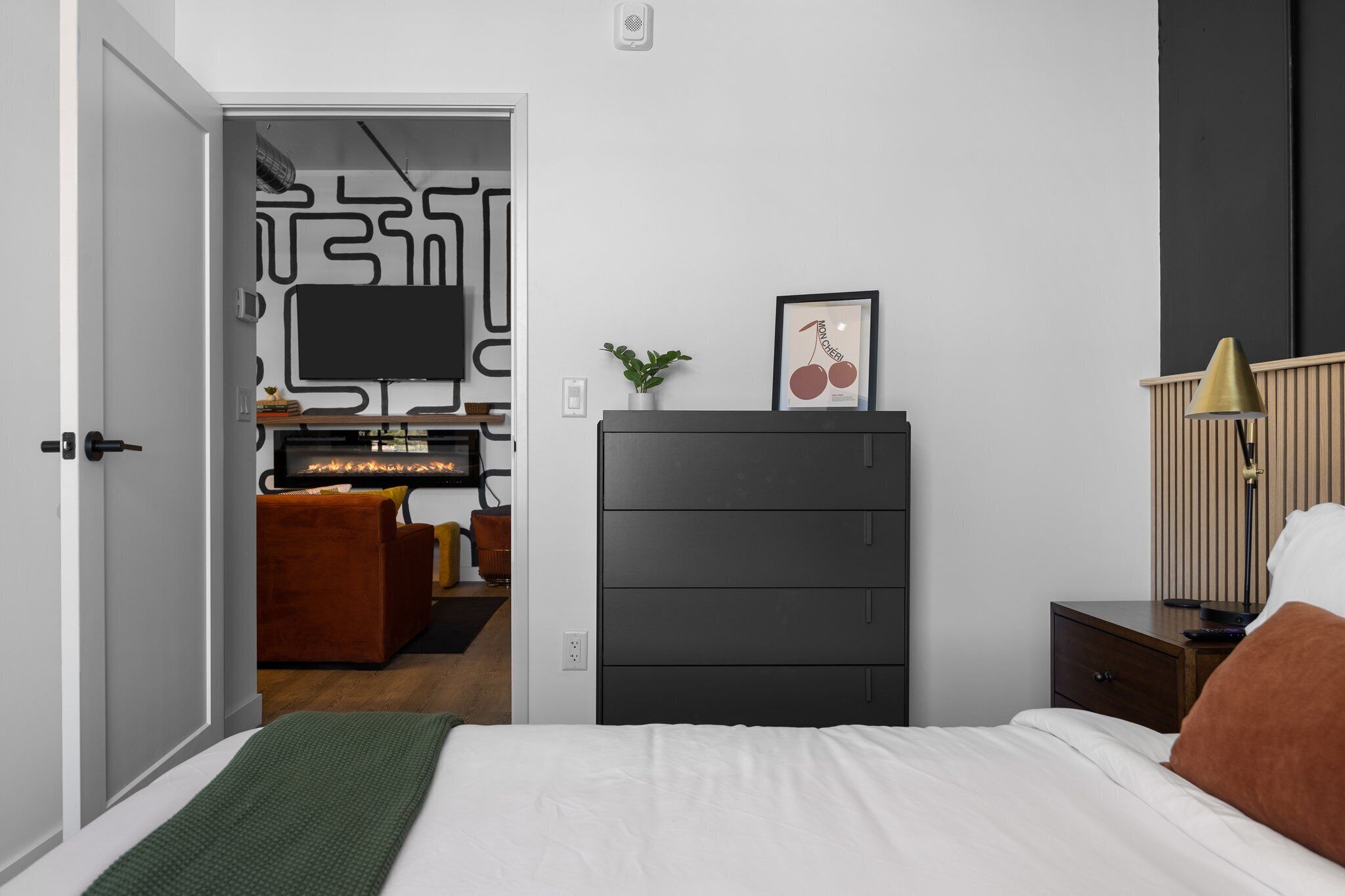 Ein modernes Schlafzimmer mit einem Bett, einem Schminktisch, einem Fernseher und einem Schreibtisch mit Stuhl.