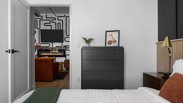 Ein modernes Schlafzimmer mit einem Bett, einem Schminktisch, einem Fernseher und einem Schreibtisch mit Stuhl.