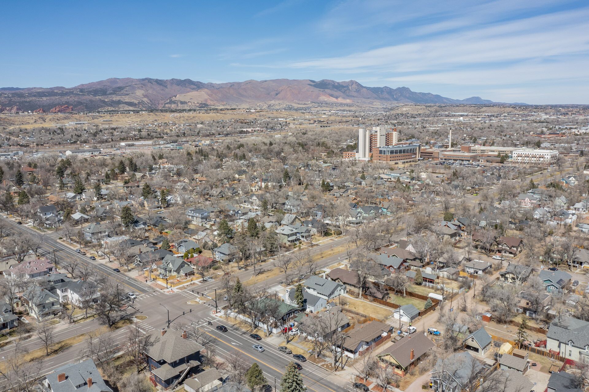 An aerial view of a residential area with houses, roads, and distant mountains.