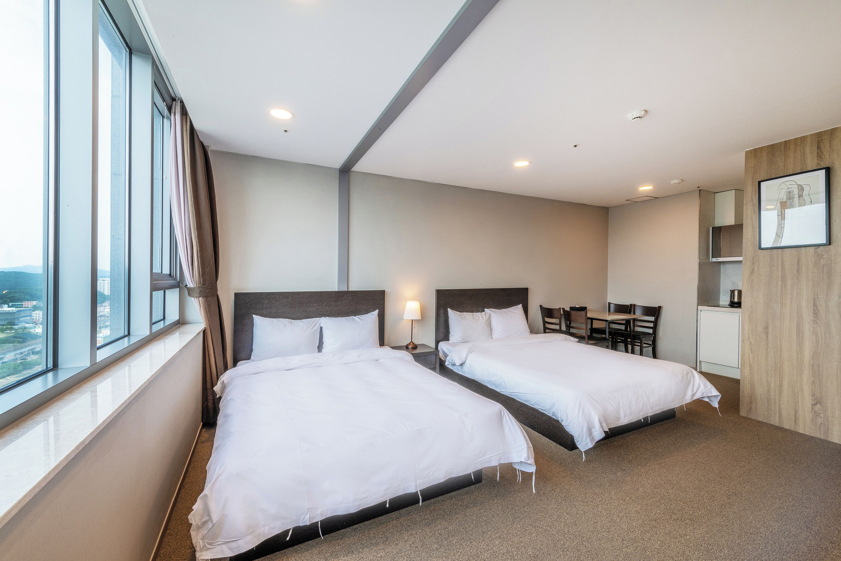 A hotel room with two beds, a desk, and a chair.