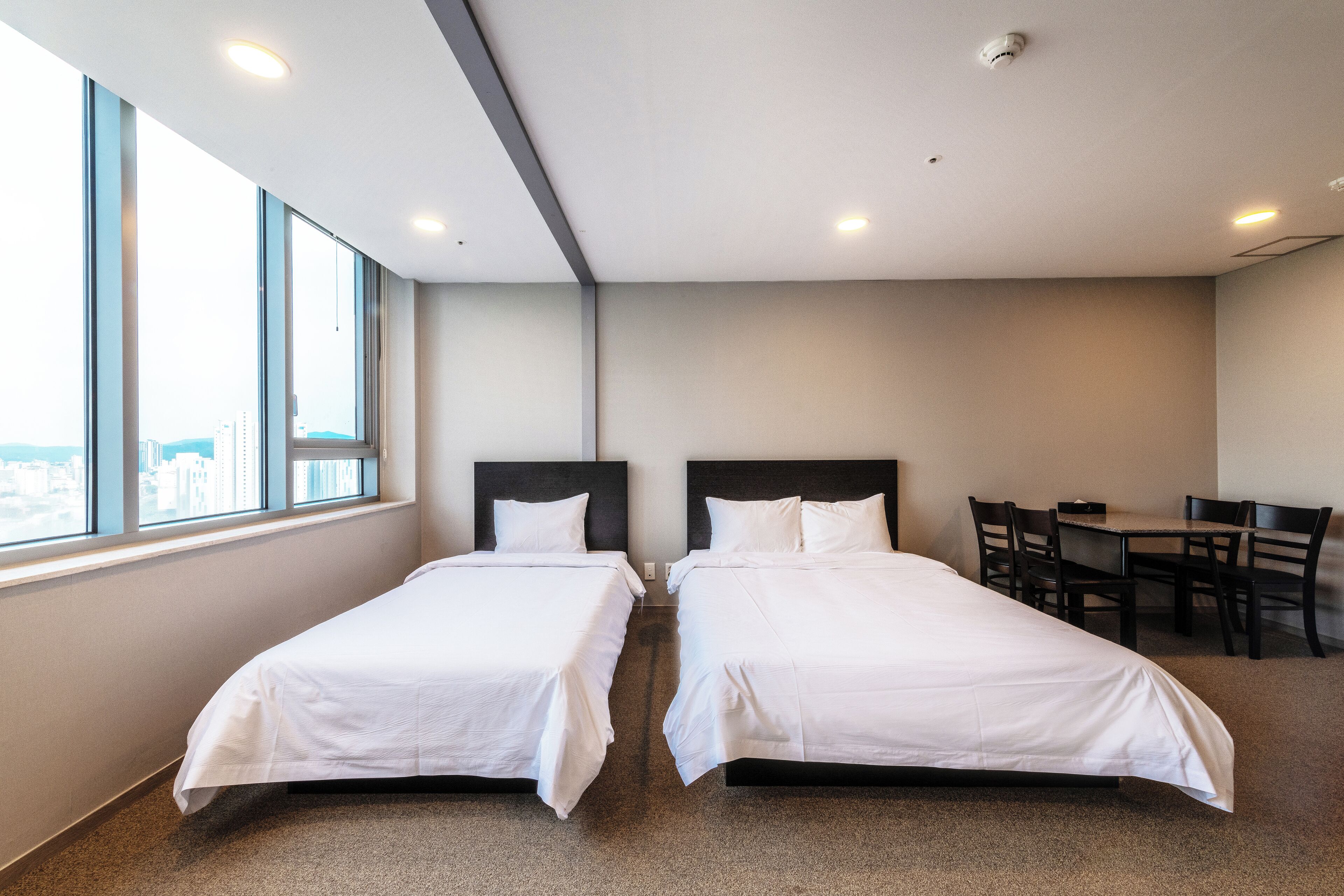 A hotel room with two beds, a desk, and a chair.
