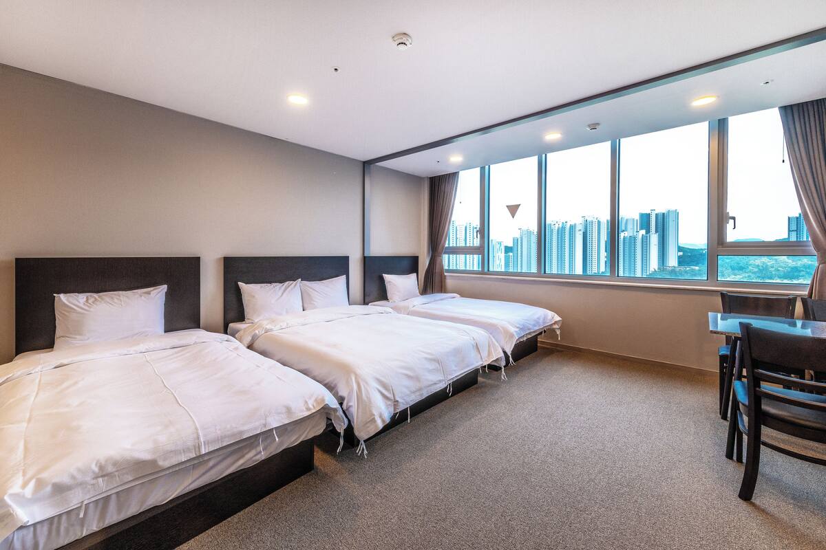 Une chambre d’hôtel avec deux lits, un bureau et une grande fenêtre donnant sur la ville.