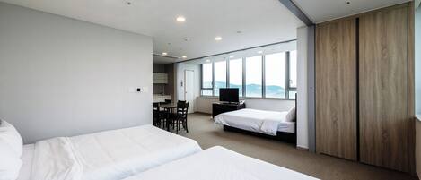 Una habitación de hotel moderna con dos camas, un escritorio y un televisor.