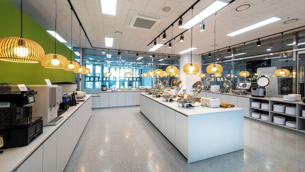 A modern kitchen area with a central island, various appliances, and hanging pendant lights.