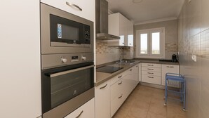 Une cuisine moderne dotée d’appareils électroménagers en acier inoxydable, de meubles blancs et d’un chariot bleu.
