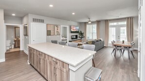 Un apartamento moderno con cocina, comedor y sala de estar. Cuenta con una isla grande en la cocina, una mesa de comedor con sillas y un sofá en la sala.