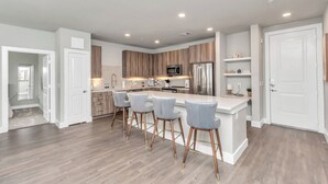Una cocina moderna con una isla central, taburetes de bar y electrodomésticos integrados.