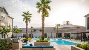 Un área de piscina con sillas de descanso y palmeras.
